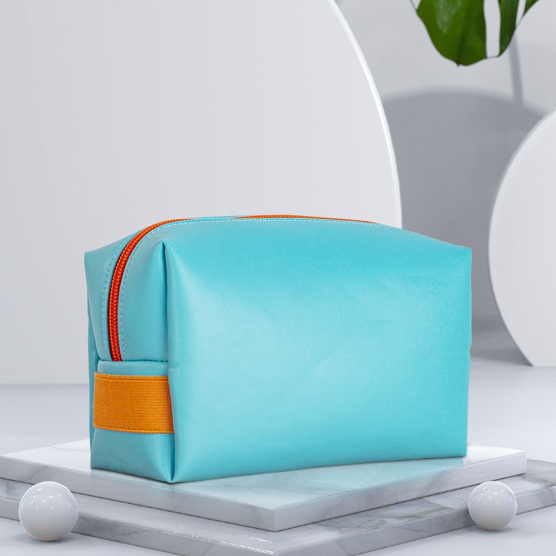 Angled view of custom light blue PVC toiletry bag with orange zipper