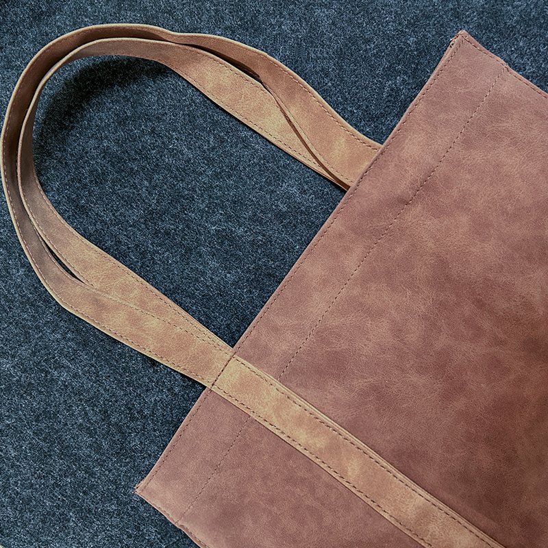 Upright brown suede PU tote bag placed on a wooden table with tea accessories background