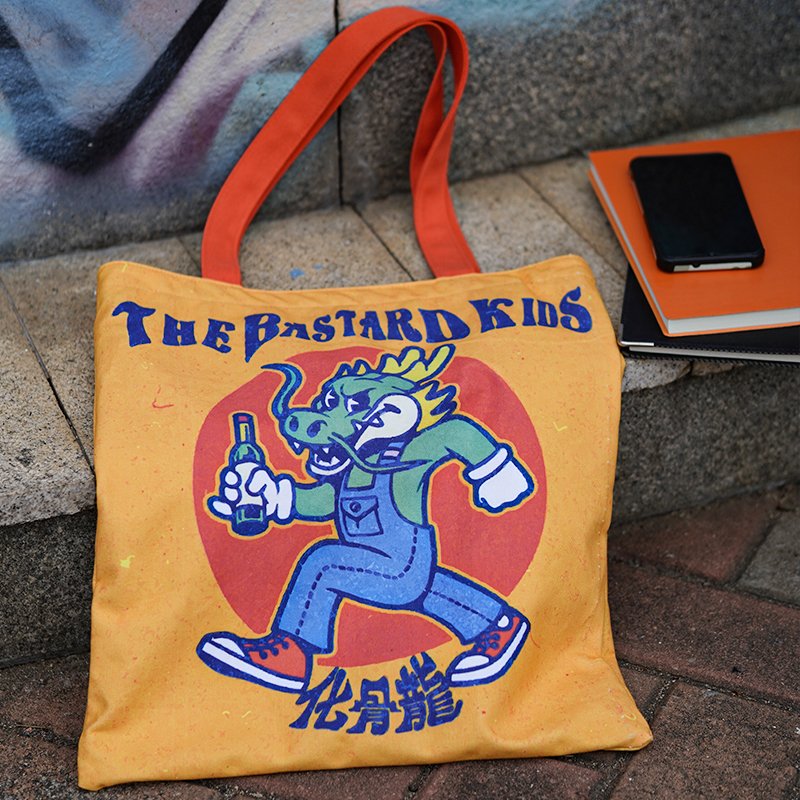 Custom yellow canvas tote bag with graphic print placed on stairs next to a matching notebook and smartphone for a lifestyle scene
