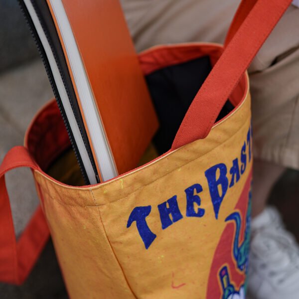Open custom canvas tote bag with a notebook inside, showing the peach skin lining and inner pocket