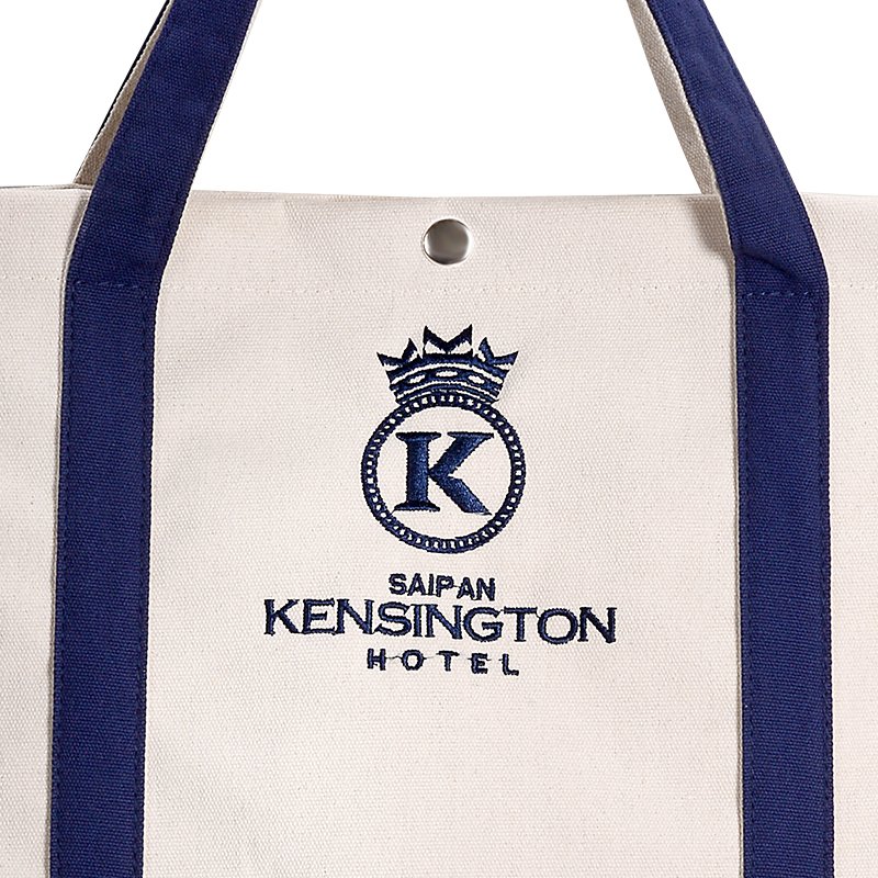 Close-up of premium embroidered hotel logo and snap button closure on canvas tote bag
