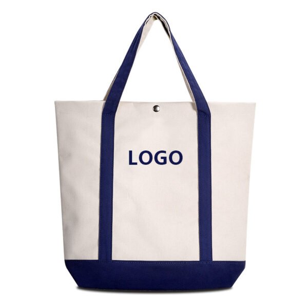 Custom two-tone canvas tote bag with navy blue handles and bottom, featuring a metal snap button and logo placement area. Studio shot on white background.