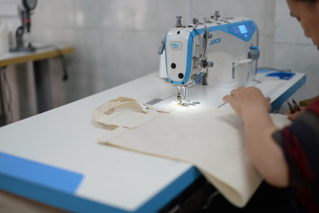 Skilled female worker attentively sewing a custom canvas tote bag at Gongfu Pinke's factory.